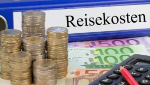 Geld, ein Taschenrechner und ein Aktenordner mit der Aufschrift "Reisekosten"