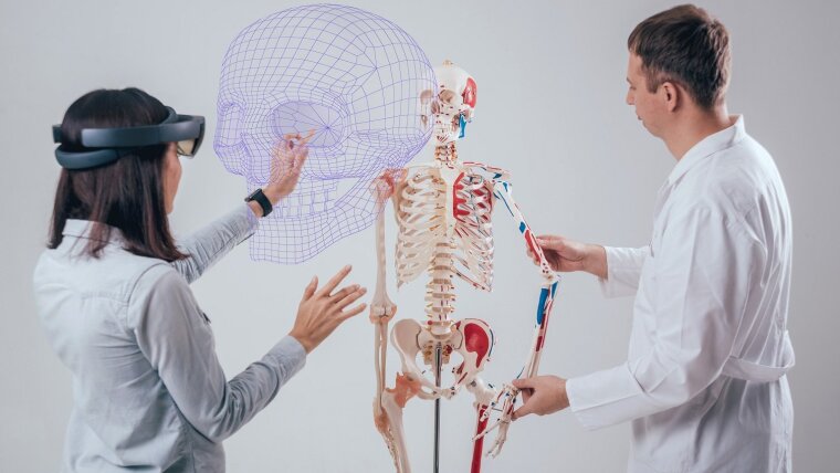Eine Frau mit einer VR-Brille und ein Mann untersuchen ein menschliches Skellett mithilfe von Mixed Reality